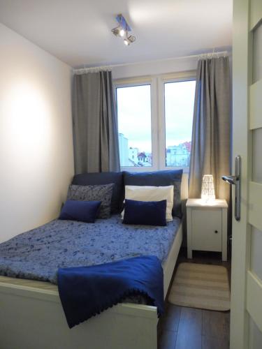 ヘルにあるApartament Marynarski Helのベッドルーム1室(青いシーツ付きのベッド1台、窓2つ付)