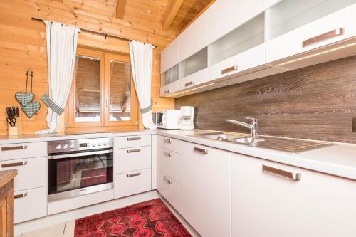 a kitchen with white cabinets and a red rug at Alpen-Chalets Achensee in Maurach