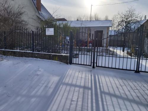 a fence in front of a house with snow at DéeL apartman in Nyíregyháza