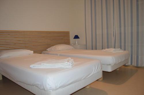 two beds in a hotel room with white towels on them at Apartamentos Cabanas Golf in Tavira