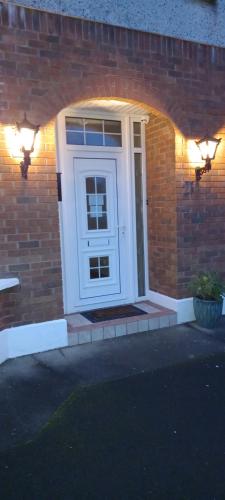 a white door on a brick house with lights at Woodhaven Manor h91rc9d in Galway