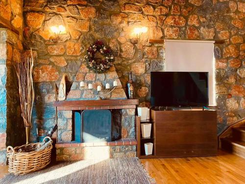 eine Steinmauer mit einem TV und einem Kamin in der Unterkunft Chalet D'elite in Palaios Agios Athanasios