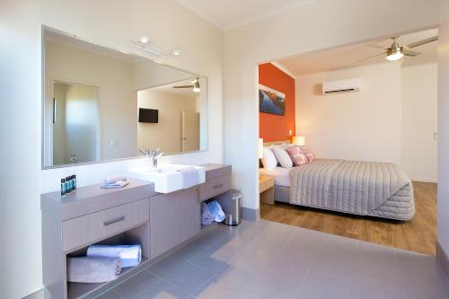 a hotel room with a large bed and a large mirror at Freshwater East Kimberley Apartments in Kununurra