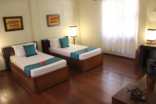 a room with two beds and a table in it at Asia Grand View Hotel in Coron