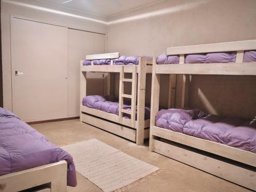 a room with three bunk beds with purple sheets at La Deseada Casa de Campo in La Granja