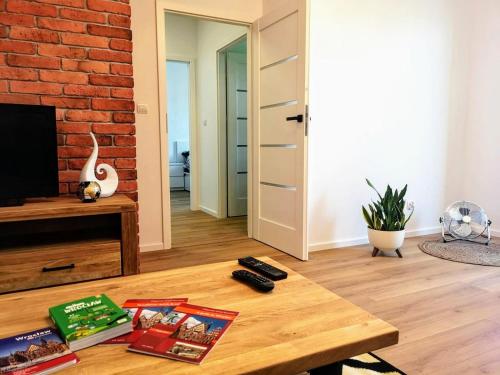 a living room with a coffee table and a brick wall at Nowoczesny apartament na Promenadach Wroclawskich in Wrocław
