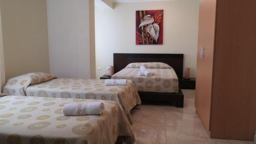 a hotel room with two beds and a painting on the wall at Hotel Las Flores in Ica