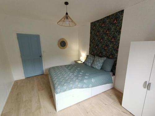 a bedroom with a bed with a blue comforter at Cosy T2 in Montbrison