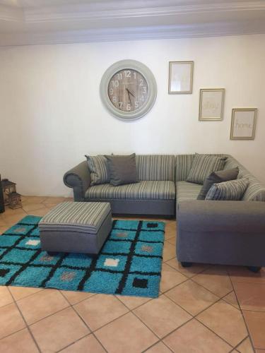 uma sala de estar com um sofá e um relógio na parede em Genie's Nest 5 em Pretoria