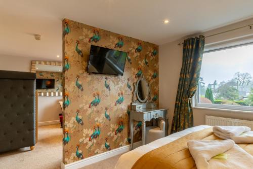 a bedroom with a wall with colorful birds on it at Holly Lodge Guest House with FREE off site health club in Windermere