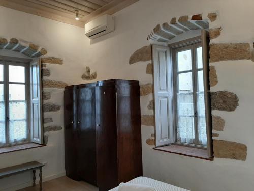 a room with a wooden cabinet and two windows at En Patmo Holiday Home in Patmos