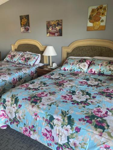 1 dormitorio con 2 camas con colcha de flores en HOMETOWN INN, en Charles City