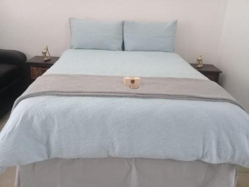 een wit bed met een witte deken en blauwe kussens bij Genie's Nest Ooie 1 in Pretoria