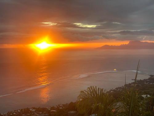 a sunset over the ocean with the sun setting at Globe trotter Lodge Tahiti in Punaauia