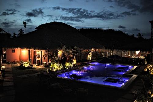 a pool with blue lights in a resort at night at Pousada Vila Camurim in Atins