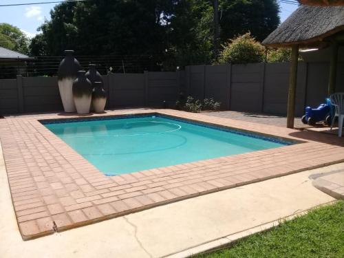 a small swimming pool in a backyard with vases at Genie's Nest Ooie 2 in Pretoria