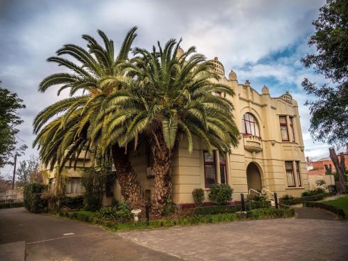 a palm tree in front of a building at Toorak Manor Hotel in Melbourne