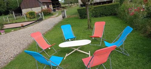 a group of chairs and a table in the grass at Maison normande au bord de Seine, Le Verger de Pacôme in Anneville-Ambourville