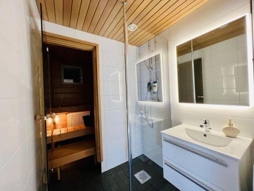 ein Bad mit einem Waschbecken und einer Glasdusche in der Unterkunft Spacious City Center Apt - Sauna - Self Check in in Rovaniemi