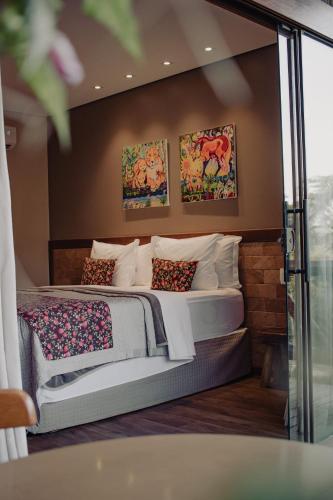 a bedroom with two beds and paintings on the wall at Pousada Meu Talento in Alto Paraíso de Goiás