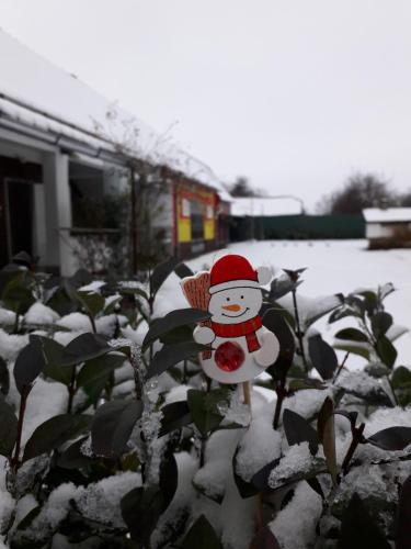 a snowman figurine in a garden covered in snow at Apartman ŠOKICA in Bizovac