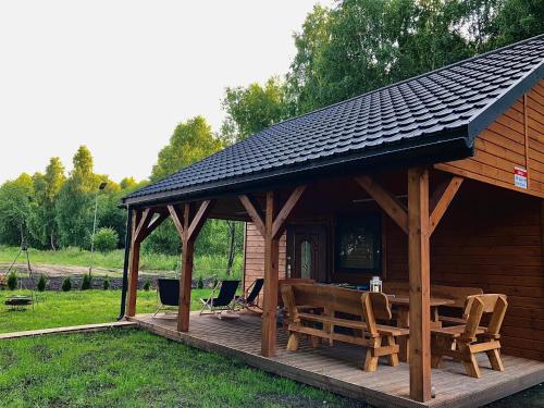 a wooden cabin with chairs and a table on a deck at DOMEK LETNISKOWY POD BRZOZAMI na Roztoczu wśród lasów, Zamość, Krasnobród, Zwierzyniec in AdamÃ³w