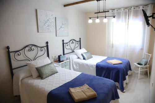 a bedroom with two beds with blue and white sheets at Casa Vazquez Sanxenxo La Lanzada in O Grove