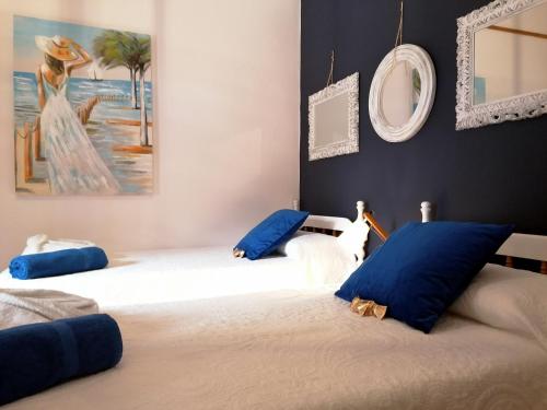 2 camas en una habitación con almohadas azules y una pintura en Villa Spa Las Tinajas, en Triquivijate