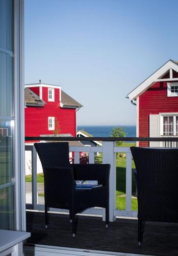 a balcony with two chairs and a red house at Pippi´s Ostseetraum in Sierksdorf