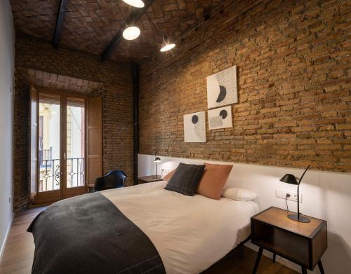 a bedroom with a large bed and a brick wall at The Gallery - BOTANIC in Granada