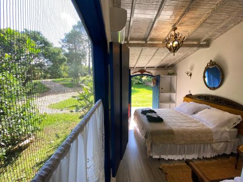 a bedroom with a bed and a balcony with a large window at Segredo da Serra Guest House in Tiradentes