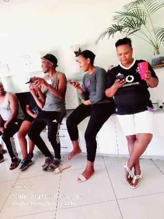 a group of people standing around looking at their cell phones at Emampingeni lodge in Bizana