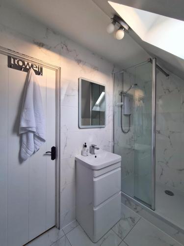 a white bathroom with a sink and a shower at The Corner Cottage in Sandwick