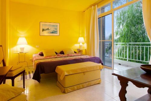 een gele slaapkamer met een bed en een groot raam bij Vcv Villa Magua in Santa Brígida