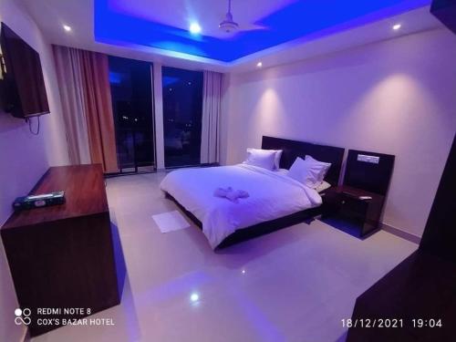 um quarto com uma cama branca e um tecto roxo em Hotel Opera Ocean em Cox's Bazar