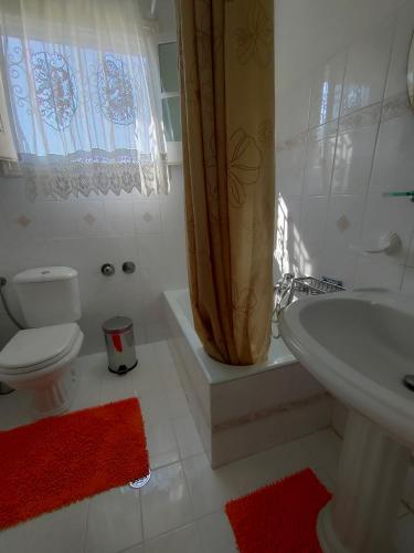 a bathroom with a toilet sink and a shower curtain at Villa Southern Comfort in Lefkimmi