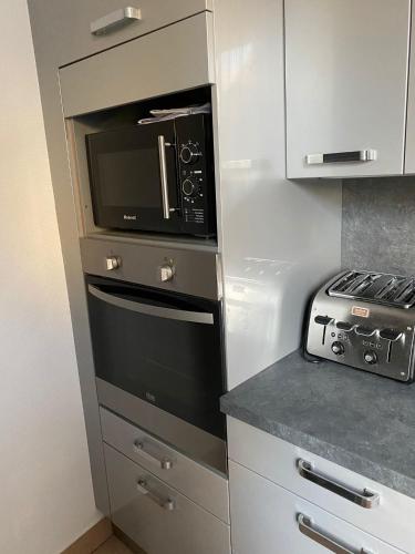 une cuisine avec un micro-ondes et une cuisinière dans l'établissement Grand F4 de 71m2 pour 6 personnes en plein centre ville Arpajon, à Arpajon