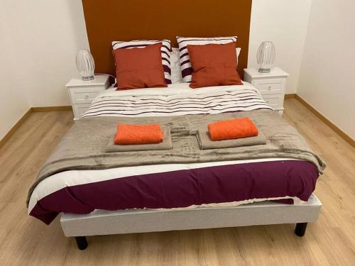 a large bed with two orange pillows on it at Grand F4 de 71m2 pour 6 personnes en plein centre ville Arpajon in Arpajon