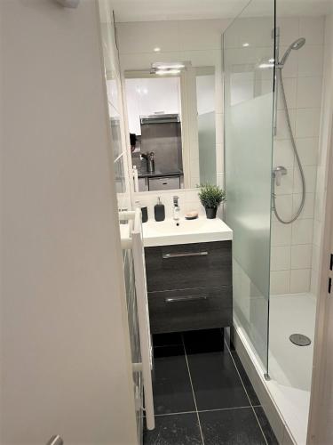 een badkamer met een douche, een wastafel en een spiegel bij Location appartement saint lary 2/4 personnes in Saint-Lary-Soulan