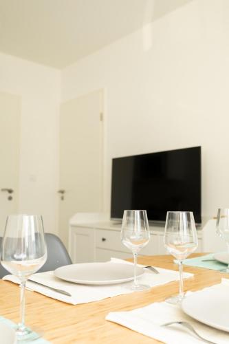 a table with three wine glasses and a tv at L'ESCAPADE entre DISNEY et PARIS in Noisy-le-Grand