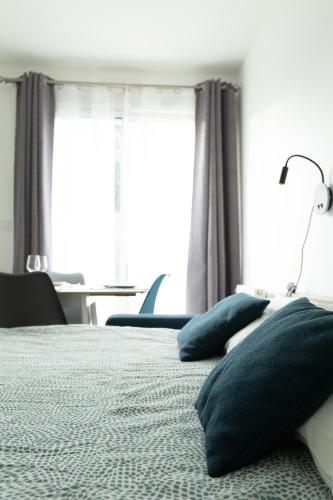 ein Schlafzimmer mit einem Bett mit Kissen und einem Fenster in der Unterkunft L'ESCAPADE entre DISNEY et PARIS in Noisy-le-Grand
