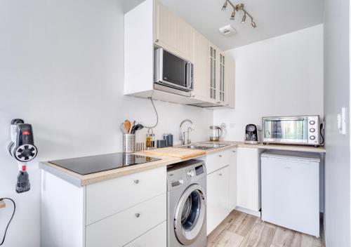 eine Küche mit weißen Schränken, einer Waschmaschine und einem Trockner in der Unterkunft L'ESCAPADE entre DISNEY et PARIS in Noisy-le-Grand