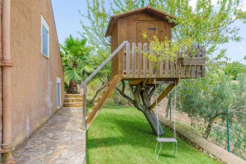 una casa en el árbol con un columpio en un patio en Es Turó de França, en Calonge