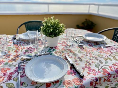 een tafel met borden en glazen en een plant erop bij Ático frontal con vistas al mar - 1ª línea Acapulco I in Oropesa del Mar