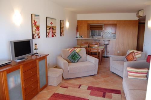 a living room with a tv and a couch and chairs at Clube Alvor Ria in Alvor