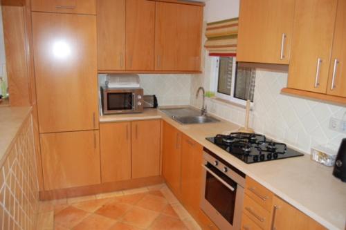 a kitchen with wooden cabinets and a stove top oven at Clube Alvor Ria in Alvor