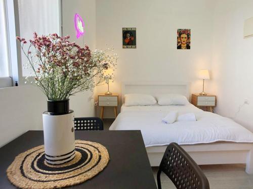 特拉維夫的住宿－Lev Florentin Apartments，一间卧室配有一张床和一张带花瓶的桌子