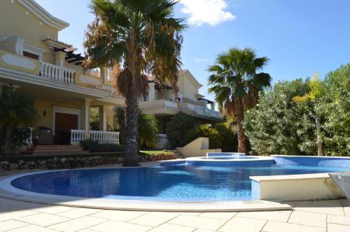 ein Swimmingpool vor einem Haus mit Palmen in der Unterkunft Belar in Tavira