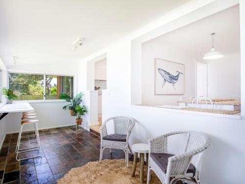 a kitchen with white walls and chairs and a table at Curleys Outlook I Pet Friendly Waterfront in Culburra Beach