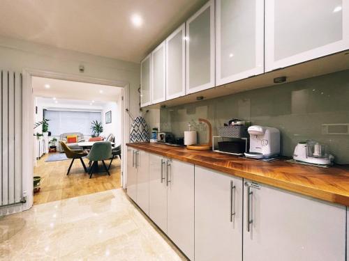 a kitchen with white cabinets and a dining room at Pamela's Place in Perivale